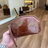 Mini sobre de cuero color marrón con cierre superior y tira de cuero para la muñeca.