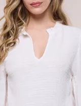 Blusa negra de silueta semi entallada confeccionada en rayón. Presenta un escote en V pronunciado con cuello mao fruncido, pechera con textura elástica en punto smock, mangas largas fluidas con frunces en los hombros y puños anchos.