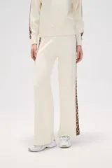 Pantalon de tejido de punto color crema, de corte ancho y tiro alto. Presenta una franja lateral con estampado animal print a lo largo de ambas piernas.
