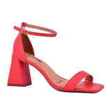 Sandalias de tacón alto color coral, con tira delgada sobre los dedos, pulsera al tobillo con hebilla y tacón geométrico. Marca Korium, modelo Amilly.