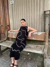 Vestido midi negro con estampado de líneas blancas, sin mangas y cuello redondo.