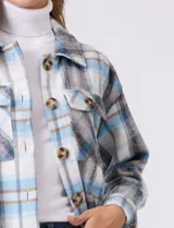 Sobrecamisa larga de tejido soft con estampado de cuadros en tonos celestes, beige y blanco. Presenta cuello con solapa, cierre frontal con botones, bolsillos aplicados en el pecho y mangas largas con puños abotonados.