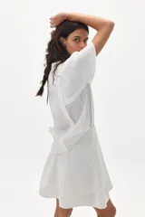 Camisa blanca de lino con mangas cortas acampanadas, cuello mao y botonadura frontal con botones de nácar.