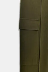 Pantalón cargo de tiro medio, color verde militar, con corte recto y bolsillos laterales de plastrón con solapa. Presenta detalles de nervios frontales y cierre con cremallera y gancho metálico.