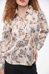 Camisa de manga larga con estampado de flores azules sobre fondo color crema, con cuello clásico y cierre frontal con botones.