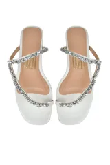 Sandalia flat color blanco con tira delantera adornada con piedras brillantes.