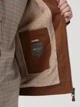 Chaqueta color marrón castaño, confeccionada en algodón 100% orgánico con interior de sherpa de fibras 100% recicladas. Cuenta con cierre frontal completo, cuello camisero, dos bolsillos frontales tipo parche y dos bolsillos interiores.