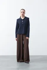 Sweater de tejido de punto color azul marino, con cuello polo amplio y cierre frontal con tres botones metálicos. Presenta mangas largas levemente acampanadas y un diseño de silueta relajada con aberturas laterales en el ruedo.