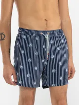 Short de baño celeste con rayas verticales blancas y estampado de flores blancas.