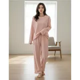 Conjunto de pijama de dos piezas confeccionado en tela de plush texturizada con diseño de rayas verticales en relieve. Incluye una remera de manga larga con cuello redondo y un pantalón de corte holgado. La remera presenta un pequeño bordado decorativo en el pecho.