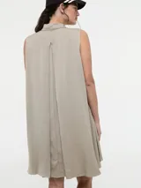 Vestido camisero corto color beige, sin mangas, con cuello clásico, cierre frontal con botones y bolsillos laterales.