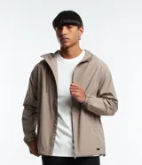 Campera ligera rompevientos color beige, con capucha y cordón ajustable, cierre frontal por cremallera y bolsillos con cierre. Cuenta con puños elásticos y diseño liso.