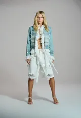 Chaqueta de jean estilo militar con alamares y botones metálicos decorativos en la parte frontal y las mangas.