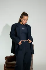 Blazer de lycra color negro, de corte oversize y diseño estructurado con solapas clásicas. Presenta detalles bordados sutiles en la solapa y en el puño de la manga.