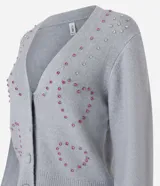 Cardigan corto gris de punto fino, con escote en V, cierre frontal con botones y apliques de pedrería formando corazones.