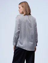 Camisa de satén estampado con diseño de cadenas en blanco y negro. Cuello con solapa, escote en V y abertura central con botones.