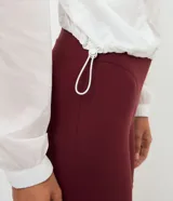 Campera cortavientos deportiva modelo cropped, color blanco traslúcido, con cierre frontal de cremallera, capucha estructurada, puños elásticos y bajo ajustable con cordón.