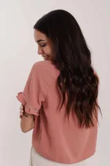 Blusa rosa con cuello redondo, mangas cortas con volados y detalle de encaje vertical en el frente.