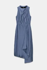Vestido midi de color azul, confeccionado con lino. Presenta cuello redondo, manga sisa y diseño sin mangas. Cuenta con bajo asimétrico y detalle de vuelo en la parte frontal.