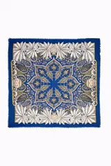 Chal de color azul con estampado paisley y motivos florales en tonos beige, blanco y verde. Los bordes tienen un acabado deshilachado.