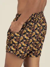 Short de baño con estampado floral en tonos marrones y amarillos, con cordón ajustable en la cintura, bolsillos laterales y trasero con cierre, y suspensor de malla fina hipoalergénico.