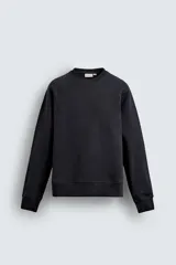 Sudadera de corte relajado confeccionada en algodón compacto con interior de rizo. Presenta cuello redondo, mangas largas tipo raglán y terminaciones en rib.