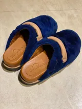 Pantuflas cerradas de cuero azul con detalle de hebilla y suela de goma.