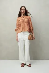 Blusa estampada de caída fluida con cuello redondo y lazos frontales, diseño con cortes horizontales y frunces, mangas largas con puños elastizados.