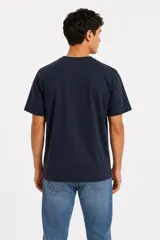 Remera de manga corta color azul marino, con cuello redondo y diseño holgado. Presenta un pequeño texto sutil estampado en el centro del pecho.