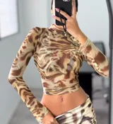 Top corto de mesh color marrón con estampado abstracto en tonos marrones y beige, de mangas largas y cuello alto.