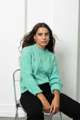 Buzo de tejido de punto color verde menta, con cuello redondo y diseño de ondas en relieve. Presenta mangas largas con puños acanalados y un corte holgado.