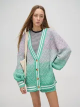 Cardigan oversize de algodón con diseño tejido a rombos en tonos degradados de marrón y blanco. Presenta cuello en V, cierre frontal con botones de madera y puños y dobladillo con rayas blancas.