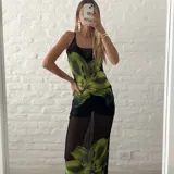 Vestido largo de microtul negro con estampado de flores verdes.