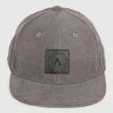 Gorra tipo jockey de corderoy gris con parche cuadrado de cuero sintético negro en el frente que presenta un logo grabado y la frase 'Always bet on black'.