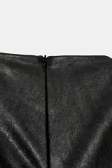 Vestido corto de efecto piel con cuello barco y diseño sin mangas. Presenta un bajo abullonado con elástico interior y cierre de cremallera en la espalda.