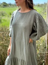 Vestido verde oliva de lino, corte suelto, con mangas abullonadas y volado en el ruedo.