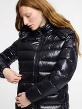 Campera puffer larga de nylon color negro, con cuello alto y capucha desmontable. Tiene cierre frontal con cremallera, bolsillos laterales con cierre y logo redondo en la manga.