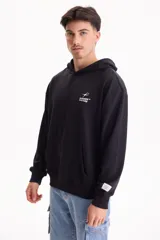 Buzo canguro oversize negro sin friza, con capucha, bolsillo delantero tipo canguro y pequeño estampado blanco en el pecho con la inscripción "Summer Culture".
