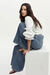 Pantalón jean de pierna ancha con calce relajado y detalles de costuras decorativas verticales en el frente, color azul.