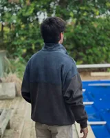Buzo de corte oversized con medio cierre frontal, confeccionado en tejido de punto en dos tonos de azul. Presenta cuello alto, mangas largas y un diseño moderno y holgado.