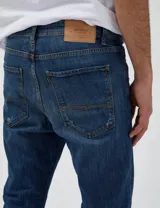 Pantalón de jean azul oscuro con roturas grandes en las rodillas y pequeñas roturas en los muslos.