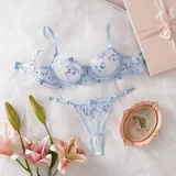 Conjunto de lencería de tul transparente color celeste, con delicado bordado floral en tonos celestes y blancos. Incluye un corpiño con aro y tirantes regulables, y una tanga regulable con tiras finas.