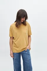 Remera de manga corta, corte holgado y cuello redondo, color mostaza con efecto lavado. Presenta un bolsillo simple en el pecho.