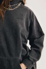 Buzo oversize negro con efecto acid wash, capucha, bolsillo canguro y mangas largas de corte raglán.