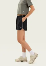 Short deportivo de color negro con ribetes blancos en los bordes y en los laterales, cintura elástica con cordón ajustable y un pequeño logo estampado en la pierna.
