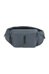 Riñonera Thule Rail 2 de 0.5L color gris azulado, diseñada para actividades deportivas. Cuenta con compartimento principal con cierre, bolsillos laterales de malla y bolsillo trasero estructurado para celular. Incluye detalles reflectivos y punto de fijación para luz.