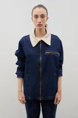 Campera de jean azul oscuro con cuello de pana en color crema. Presenta cierre frontal metálico, bolsillo con cierre en el pecho y bolsillos laterales. Diseño de corte holgado con mangas largas.