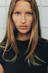 Vestido corto de cuello redondo y sin mangas, confeccionado en tela de sarga color gris oscuro. Presenta un diseño entallado en el torso con falda evasé y un cinturón integrado con arandelas metálicas doradas en la cintura. Cierre posterior con cremallera oculta.