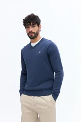 Sweater de punto color gris melange, con escote en V, manga larga y logo bordado en el pecho. Presenta puños y ruedo acanalados.