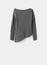Jersey de punto gris con cuello barco y diseño de bajo asimétrico. Presenta manga larga y un detalle metálico decorativo en uno de los hombros.